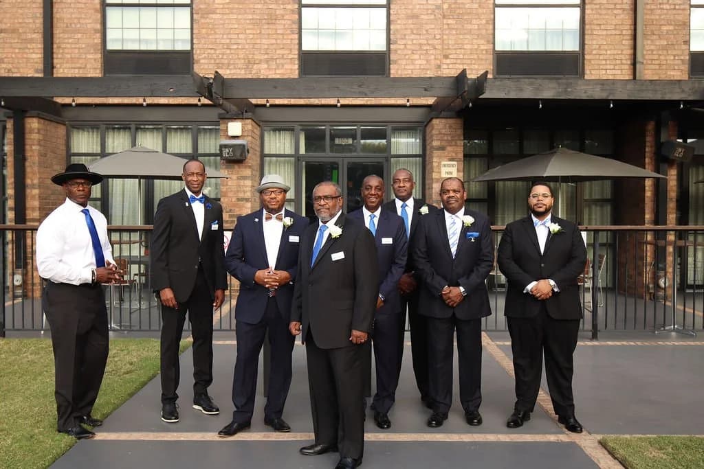 Chapter brothers in suits and blue ties posing outside a venue